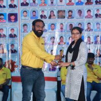 A faculty member presents an award to a girl student during the testimonials event. Faculty member giving award to girl student during testimonials event at Everest Coaching Point
